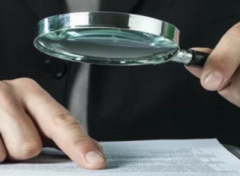 auditor revisando documentos forenses con lupa