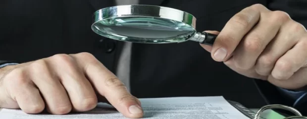 auditor revisando documentos forenses con lupa